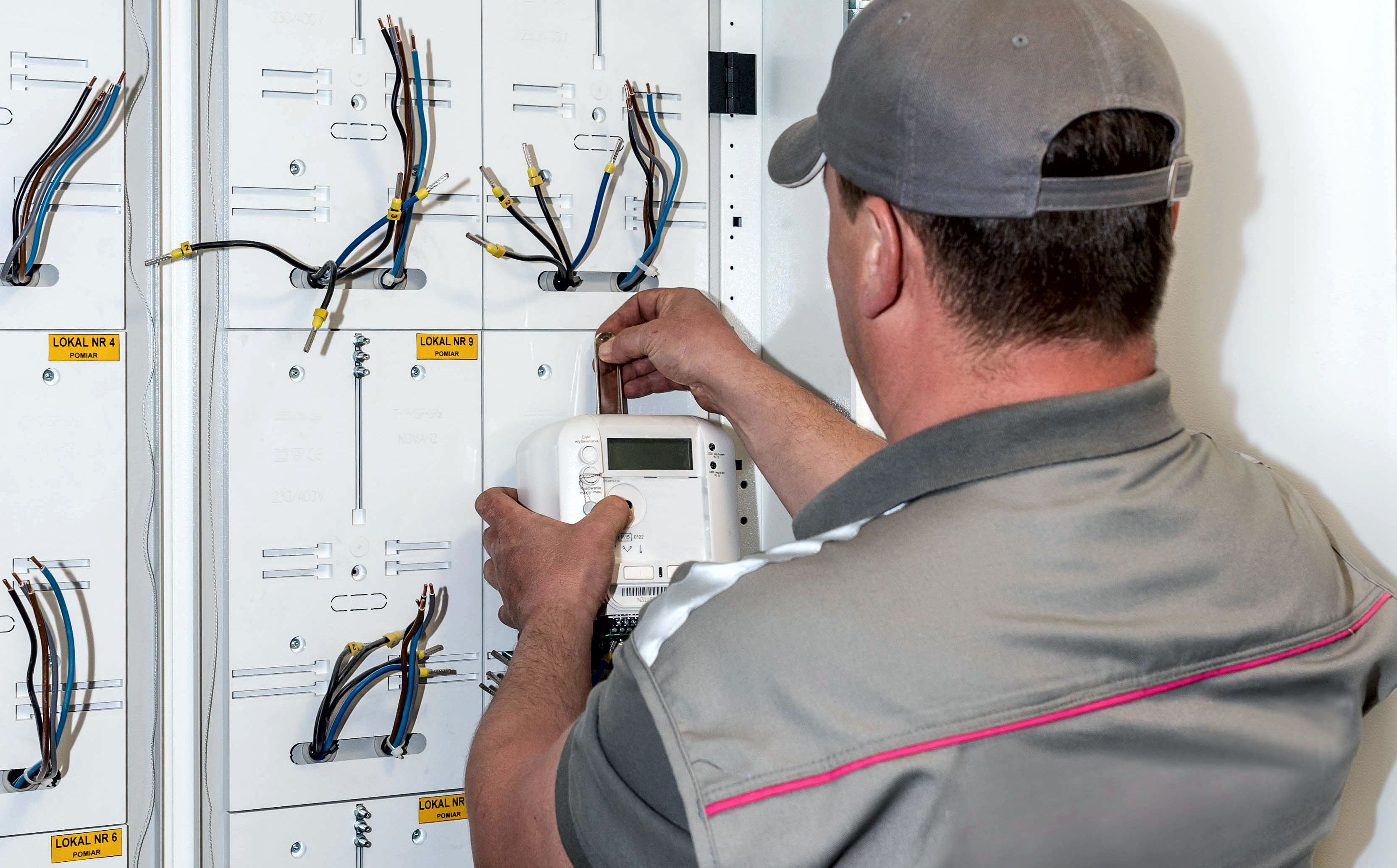 Pracownik Tauron Dystrybucja montuje nowy licznik zdalnego odczytu