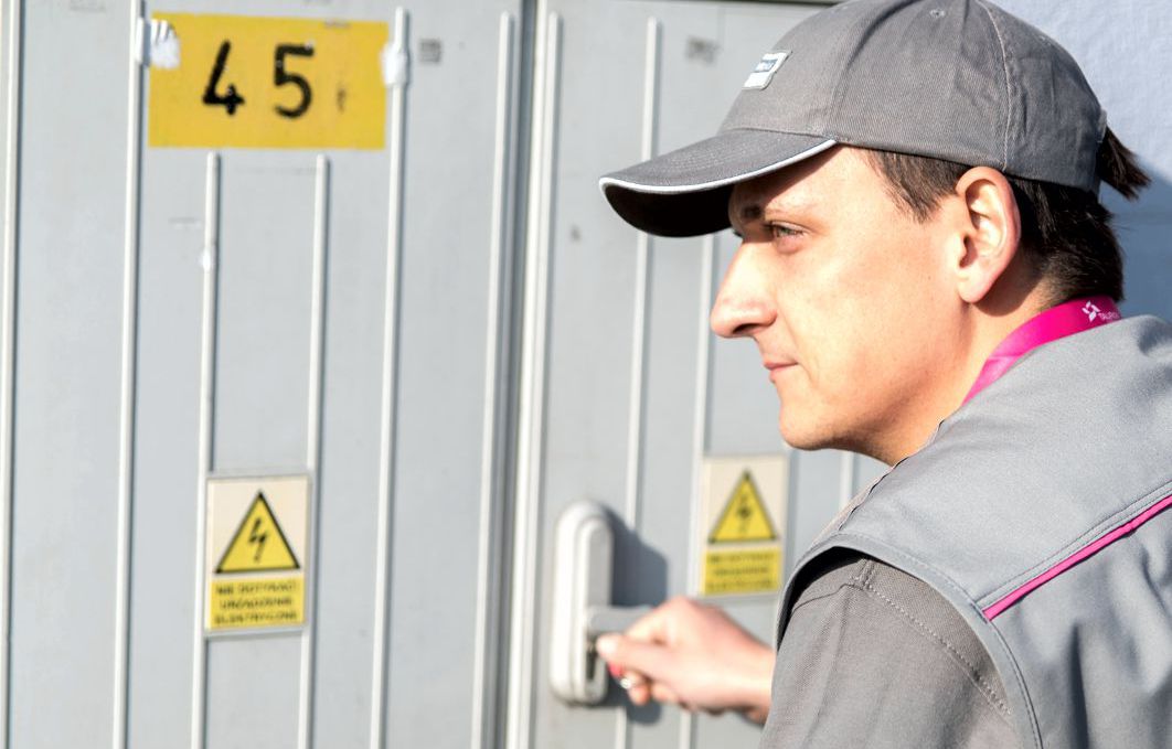 Pracownik Tauron Dystrybucja otwiera szafkę z licznikami energii elektrycznej