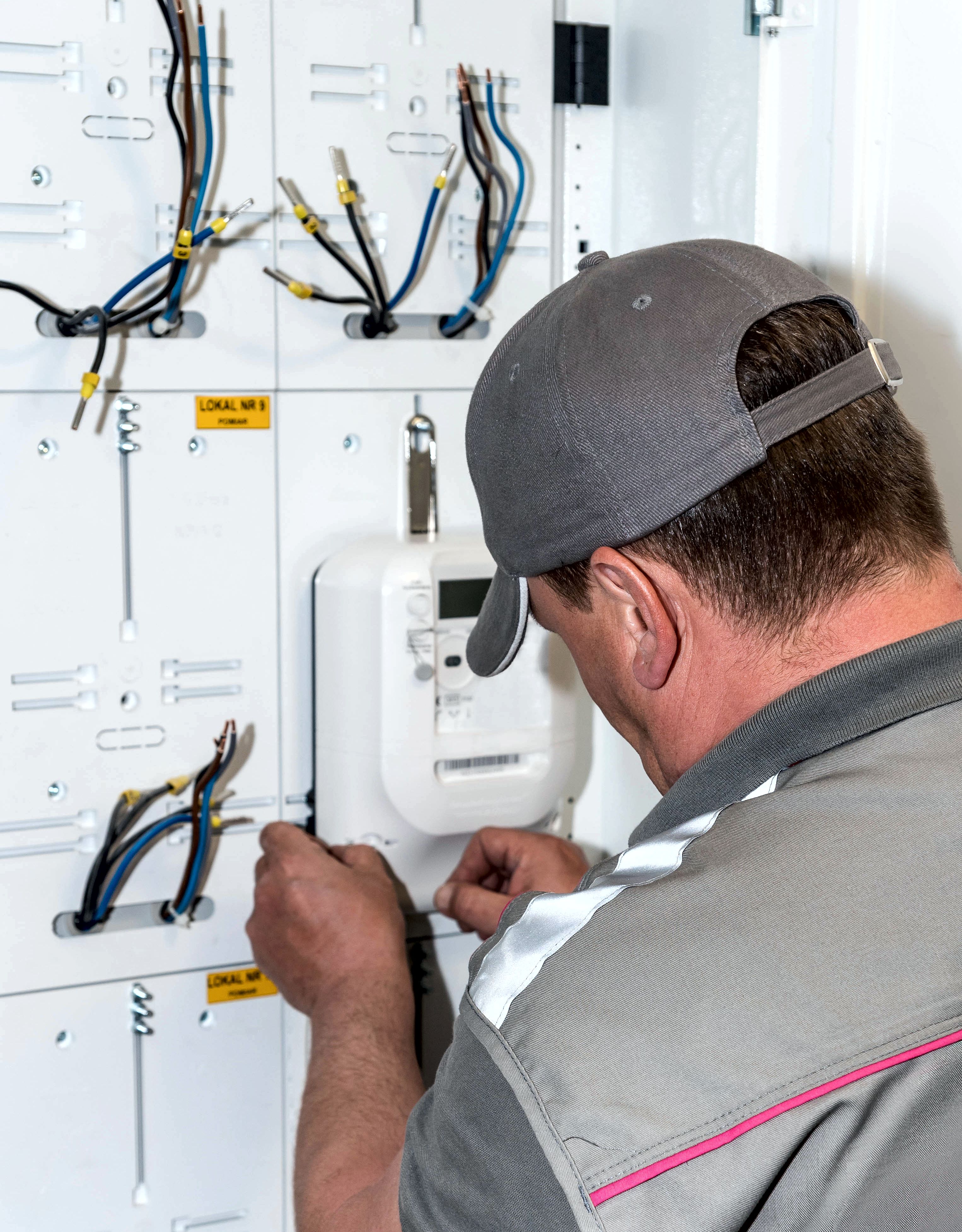 Pracownik Tauron Dystrybucja montuje nowy licznik zdalnego odczytu