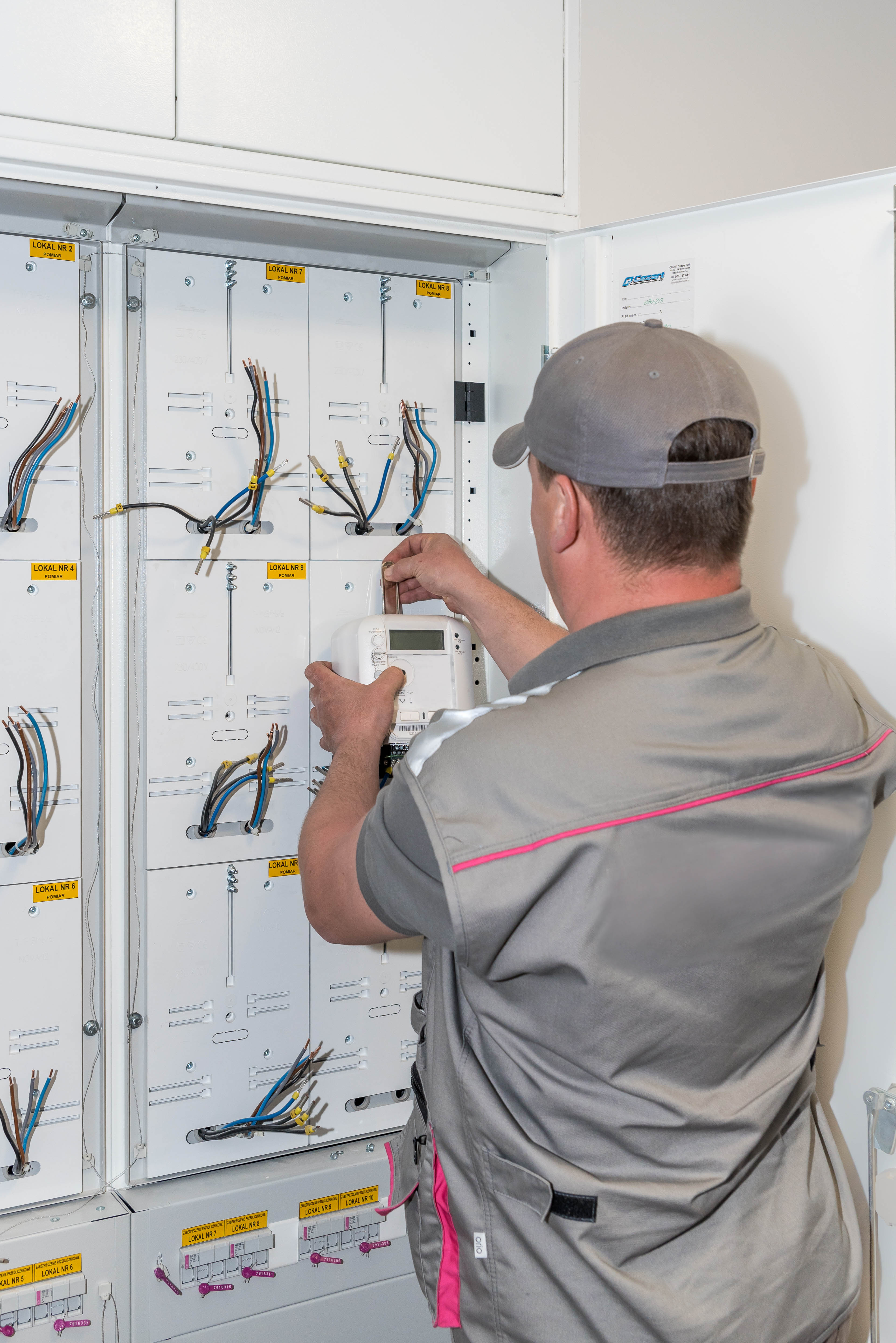 Pracownik Tauron Dystrybucja montuje nowy licznik zdalnego odczytu