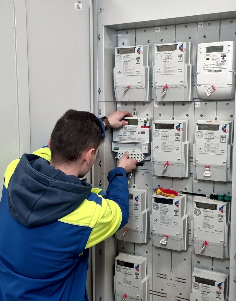 elektromonter mocuje w szafce licznik zdalnego odczytu energii elektrycznej